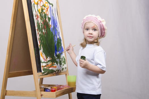 Three-year-old girl playing in the artist. Girl draws on the easel paints