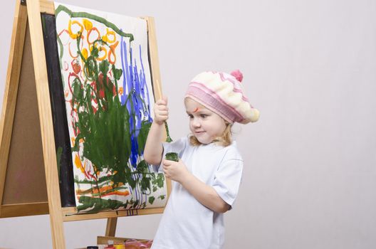 Three-year-old girl playing in the artist. Girl draws on the easel paints