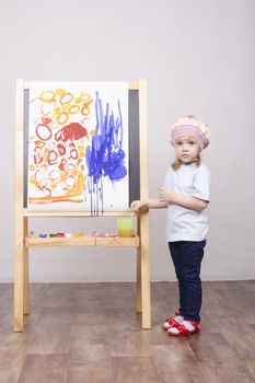 Three-year-old girl playing in the artist. Girl draws on the easel paints