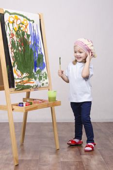 Three-year-old girl playing in the artist. Girl draws on the easel paints