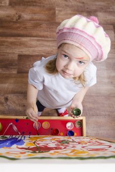 Three-year-old girl playing in the artist. Girl draws on the easel paints