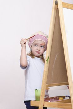 Three-year-old girl playing in the artist. Girl draws on the easel paints