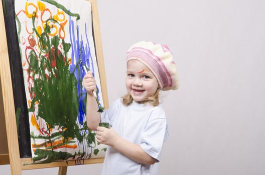 Three-year-old girl playing in the artist. Girl draws on the easel paints