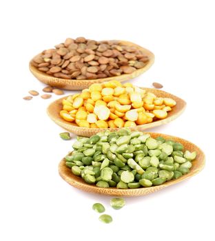Raw Green and Yellow Split Peas and Lentils in Small Wooden Saucers In a Row on white background. Focus on Foreground