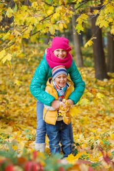 Portrait of Adorable cute boy and girl with autumn leaves in the beautiful park