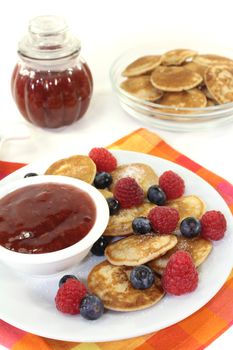 Dutch Poffertjes with berries and jelly before light background