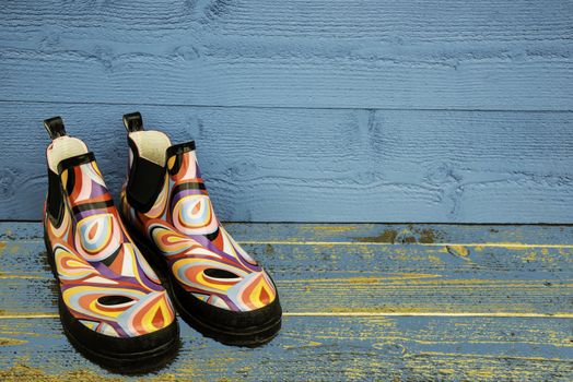 Colourful rubber boots against a blue wall