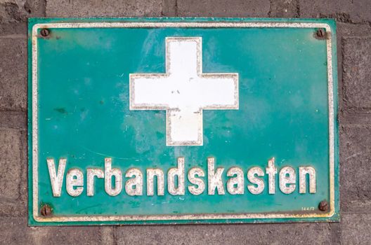 Old signboard rectangular green with a white cross and inscription aid kit.

