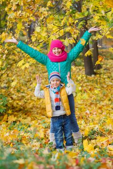 Portrait of Adorable cute boy and girl with autumn leaves in the beautiful park