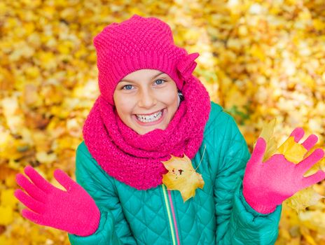 Portrait of Adorable cute girl with autumn leaves in the beauty park