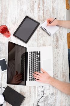 A young caucasian man working in his home office seen from above.
