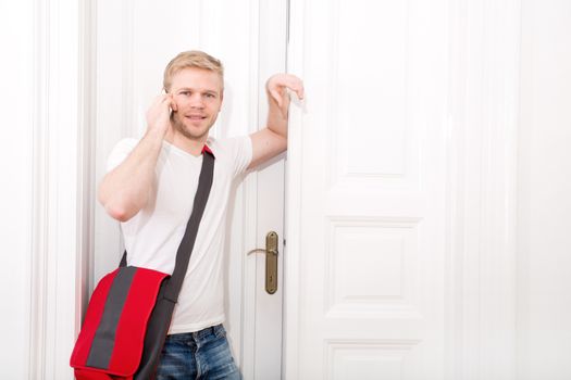 A young and busy student coming home while talking on the smartphone.