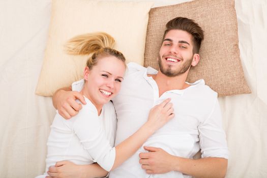 A happy young couple hugging in bed.