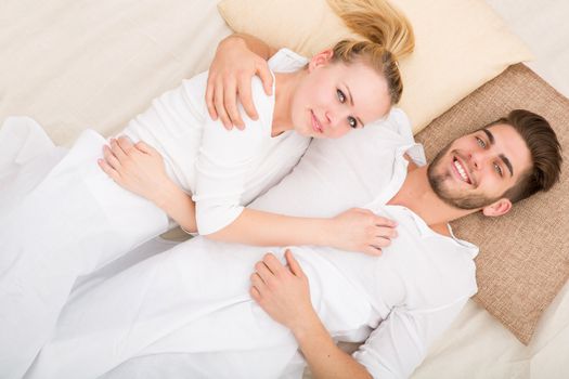 A happy young couple hugging in bed.