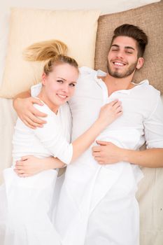 A happy young couple hugging in bed.