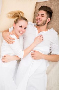 A happy young couple hugging in bed.