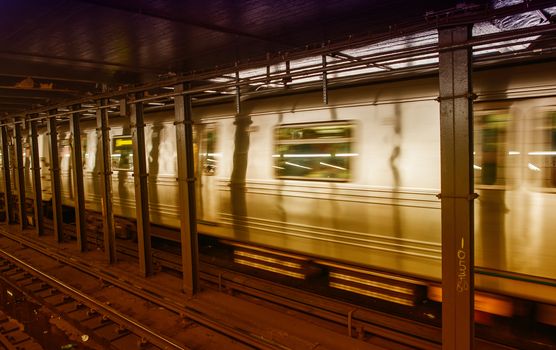 Silver Train speeding up on a subway station interior.