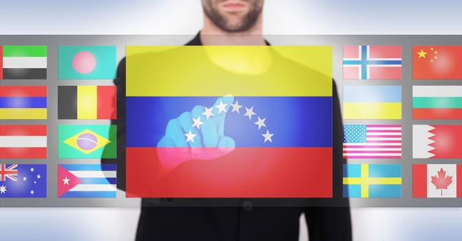 Hand pushing on a touch screen interface, choosing language or country, Venezuela