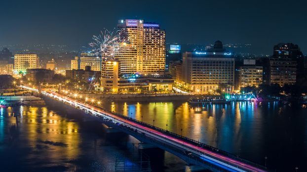 Aerial view of the city of Cairo along the Nile river at night with fireworks in the background