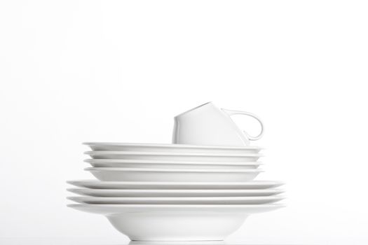 studio shot of a pile of white plate and white cup isolated on white