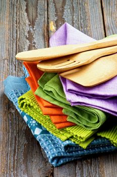 Stack of Multi Colored Cloth Napkins and Kitchen Wooden Spoons isolated on Rustic Wooden background