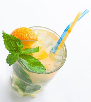 Glass of fresh made non-alcoholic drink citrus lemonade with ice cubes, mint , orange segment and straws. Top view on white background