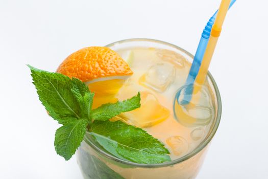 Glass of fresh made non-alcoholic drink citrus lemonade with ice cubes, mint , orange segment and straws. Top view on white background