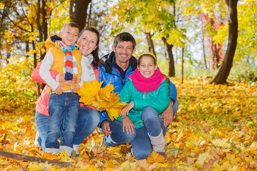 Portrait of happy family relaxing in autumn park