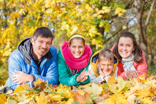 Portrait of happy family relaxing in autumn park