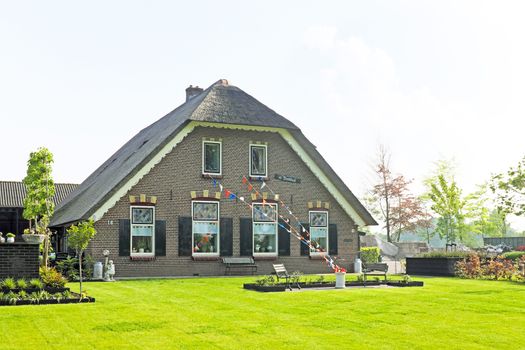 Medieval farmers house decorated with orange, white and blue flags in the countryside from the Netherlands