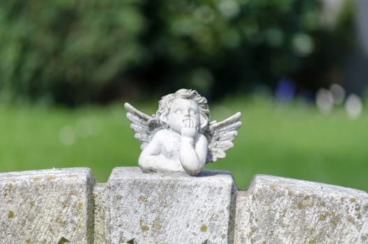 White angel figurine lying on a grave stone