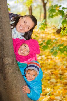 Happy family relaxing in autumn park - mother with her kids has fun in park.