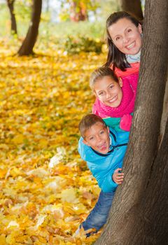 Happy family relaxing in autumn park - mother with her kids has fun in park.