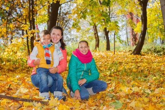 Happy mother with her kids relaxing in autumn park