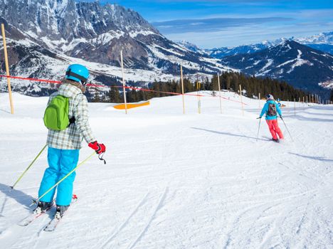 Ski, winter, snow, skiers, sun and fun - Back view of cute girl with mother enjoying winter vacations.