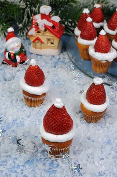 strawberries with whipped cream in the form of a Christmas hat on a muffin