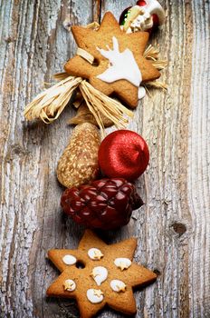 Arrangement of Christmas Ginger Cookies, Red Bauble, Fir Cone and Wooden Decoration In a Row on Rustic Wooden background