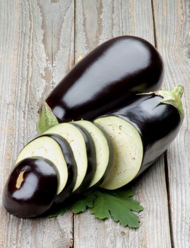 Ripe Raw Eggplants Full Body and Slices with Leafs isolated on Rustic Wooden background