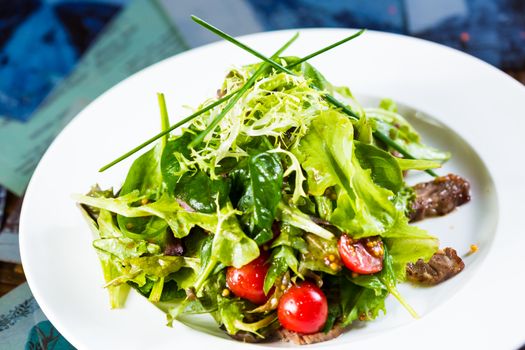 Fresh vegetable salad with meat and cherry tomatoes on white plate. Close up