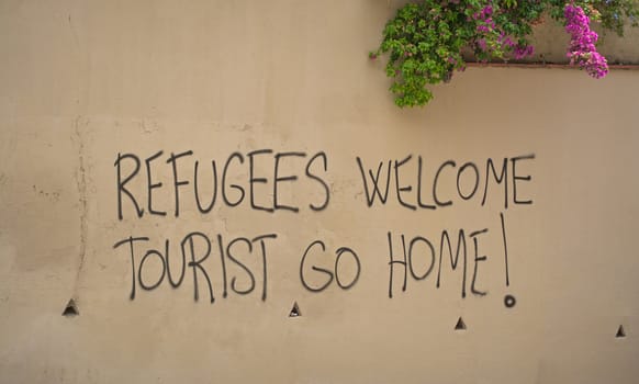 Graffiti in Barcelona, Spain, saying "Refugees welcome, Tourists go home"