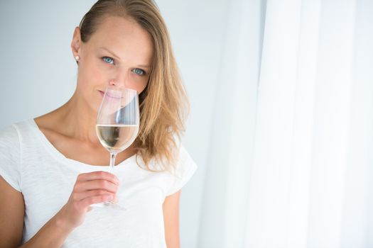 Gorgeous young woman with a glass of wine, smelling the lovely drink, savouring every sip (shallow DOF; color toned image)