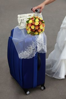 Bride with blue suitcase and a wedding bouquet