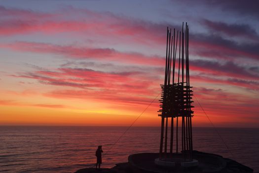 BONDI, AUSTRALIA - 23 OCTOBER, 2014; Sculpture by the Sea Annual Festival Event 2014.  Sculpture titled Save Our Souls by Cave Urban, NSW.  Silhouette against a sunrise sky. Materials, bamboo, rope,  steel, LED lights.   Price $30000