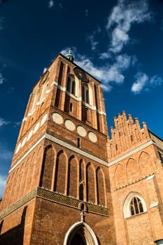 Gothic renovated cathedral St. John Church in Gdansk, Poland. Facade with white clouds on blue sky photography