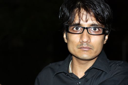 A portrait of an angry Indian man wearing glasses