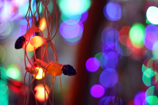 A string of colorful bulbs with a backdrop of colorful lights.