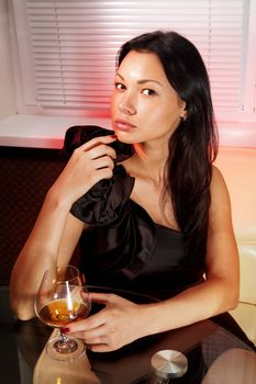 beautiful girl with glass of brandy in cafe