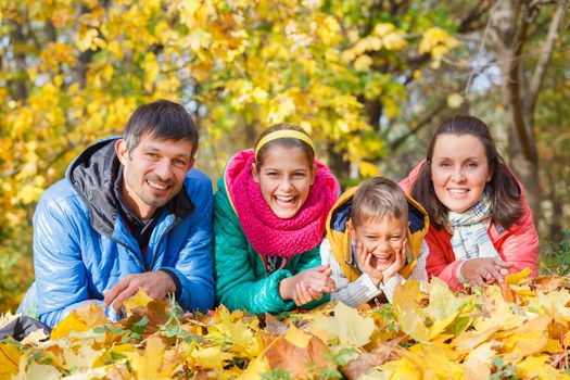 Portrait of happy family relaxing in autumn park