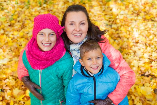 Happy family relaxing in autumn park - mother with her kids has fun in park.
