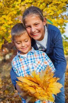 Portrait of Adorable cute boy and girl with autumn leaves in the beautiful park